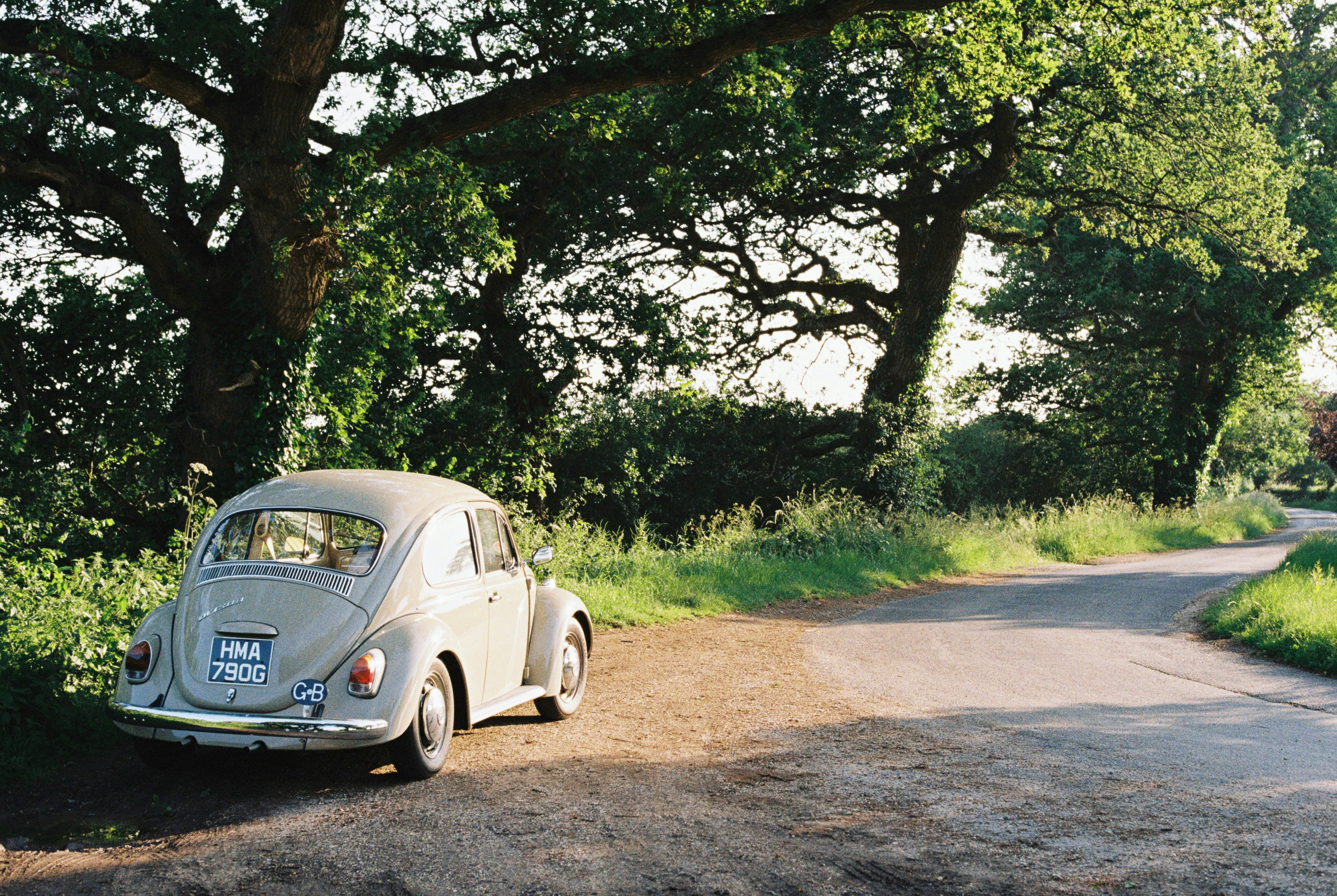 white volkswagen beetle parked on dirt road during daytime